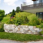Eine Steinmauer vor einem Haus in Tirol. Ein Beispiel für Gartenbau in Tirol.
